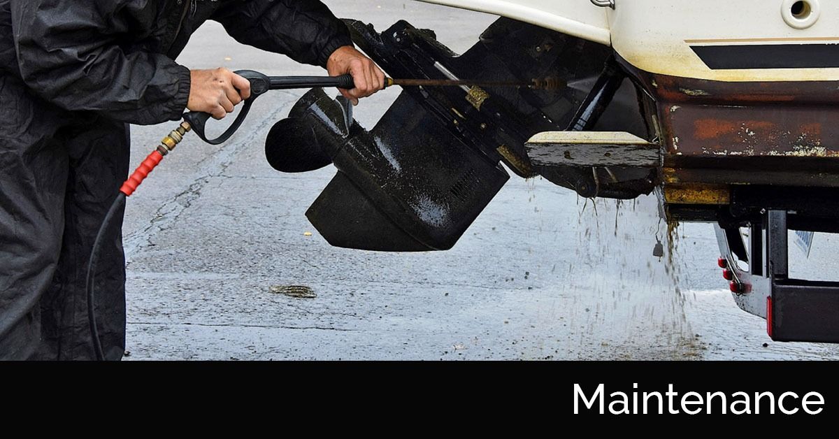 Person pressure-washes the underside of a vehicle in a maintenance setting