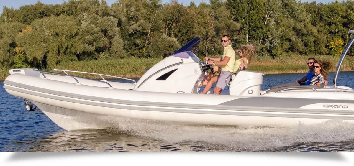 White motorboat speeding across water with two people on board and a person seated at the rear