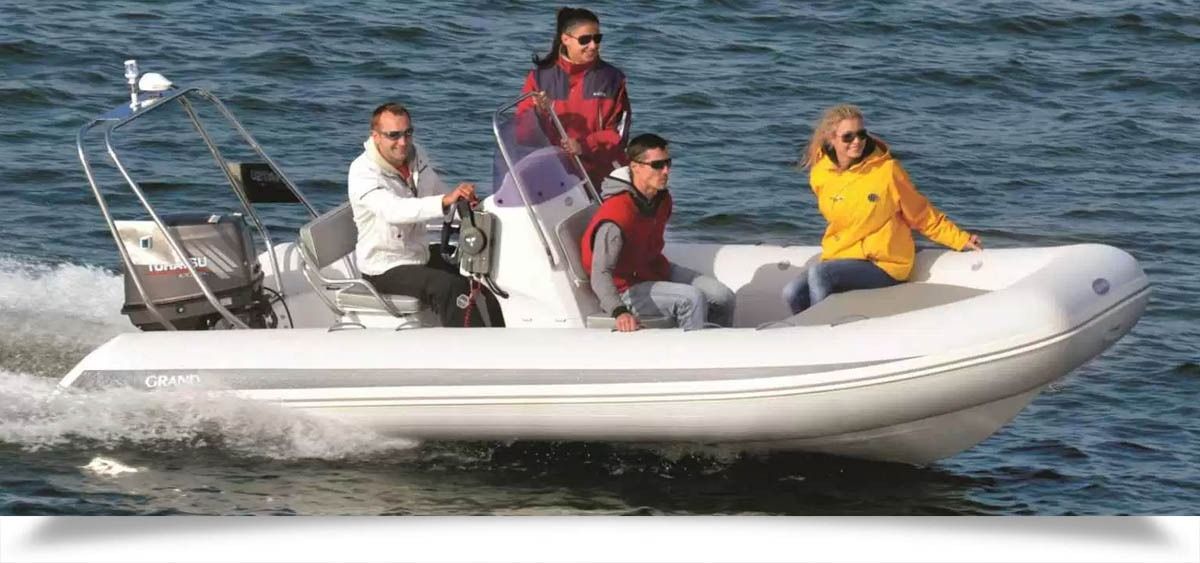 Four people on a white grand silver line 520 motorboat speeding across choppy water, wearing jackets and life vests