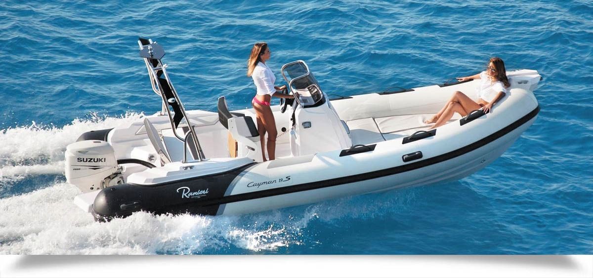 Inflatable speedboat cutting through blue water with three people aboard and a person lounging at the bow