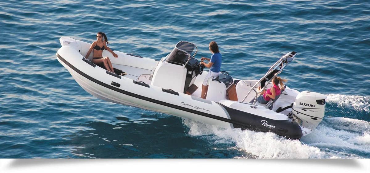 White motorboat speeding across blue water with several people aboard, creating a splash