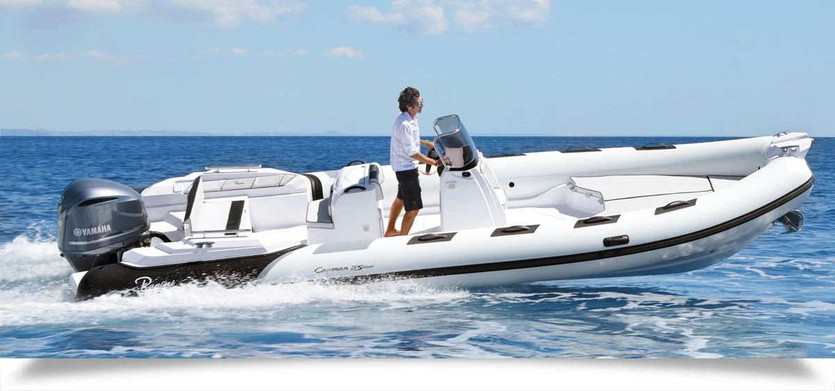 White inflatable motorboat cruising on blue water with a person standing at the helm