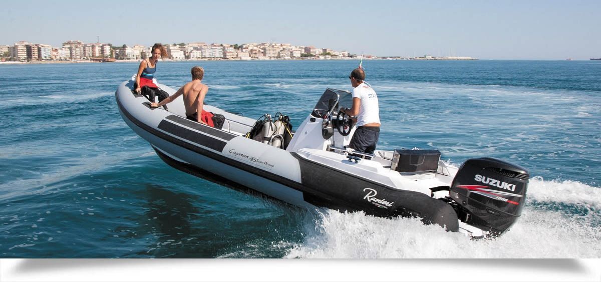 People riding a black inflatable motorboat on blue water near a coastal city