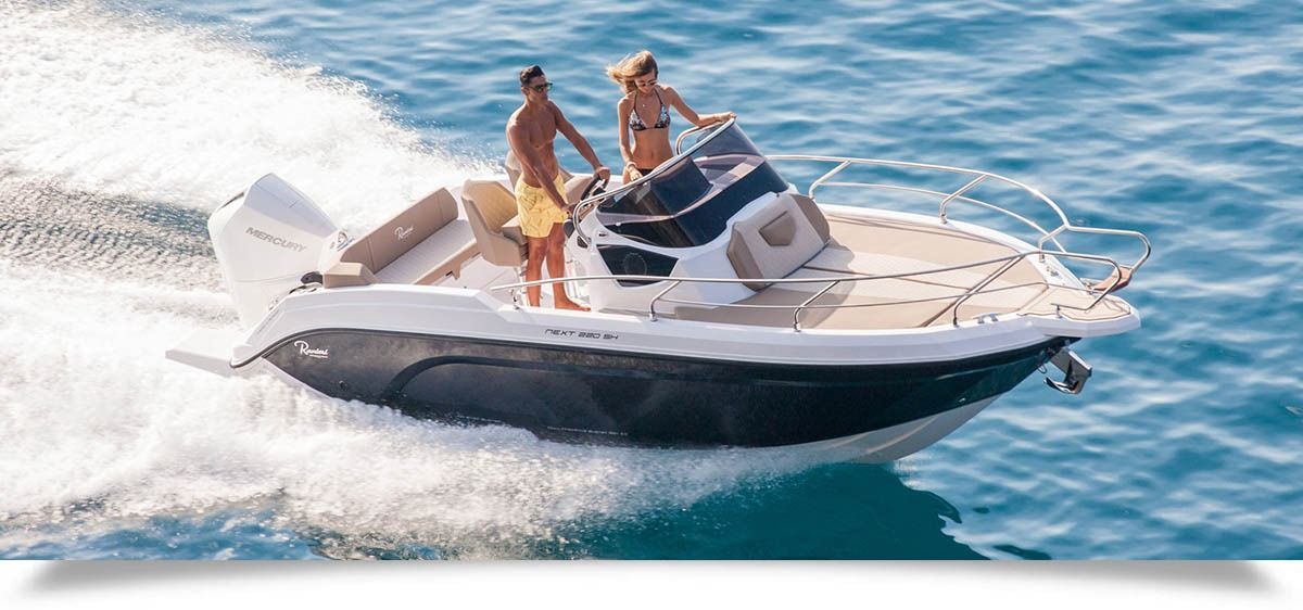 Two people on a white speedboat racing across blue water, leaving a white wake.