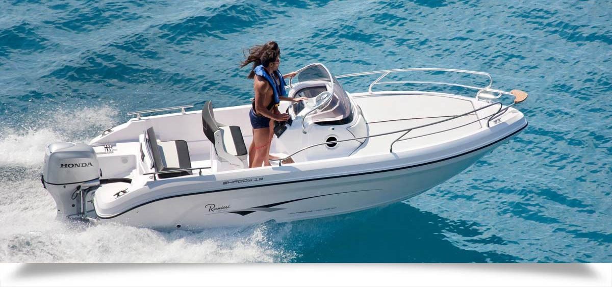 Person steering a white motorboat on bright blue water
