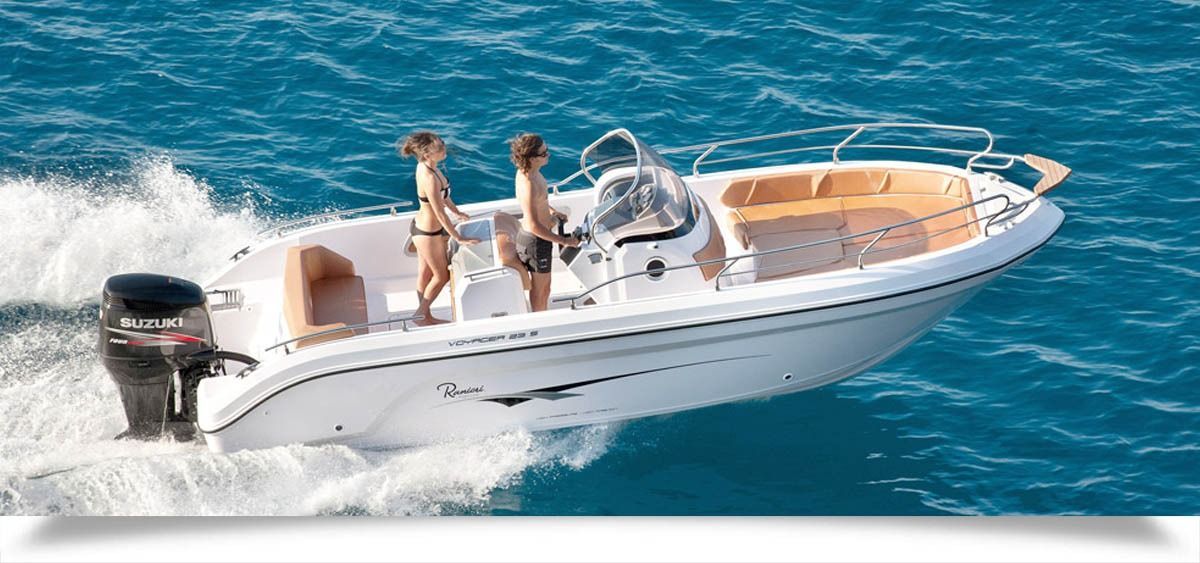 White ranieri voyager 21 Sport speedboat racing across blue water with a person at the helm and another standing aboard
