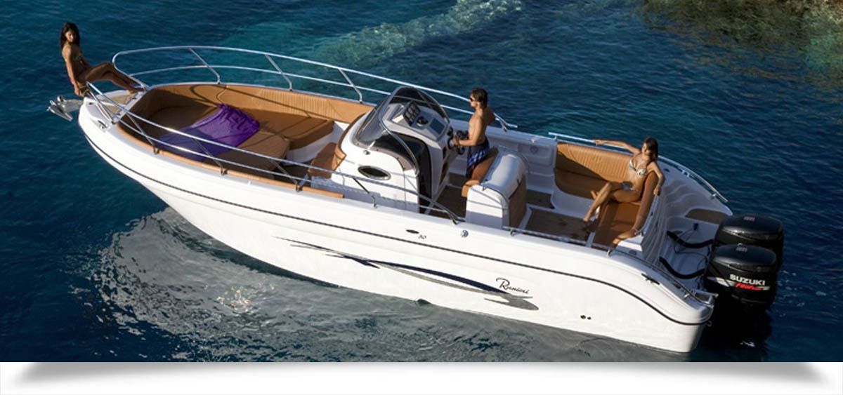 White motorboat cruising on blue water, with a person at the helm and open deck seating