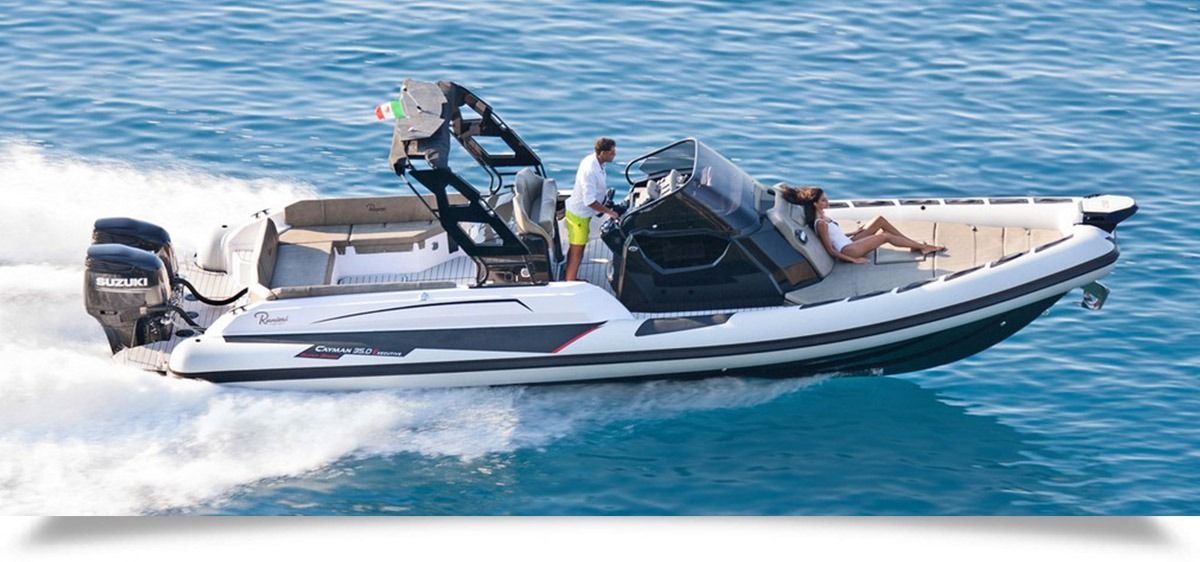 White and black speedboat cruising on blue water with two people aboard and gear on deck