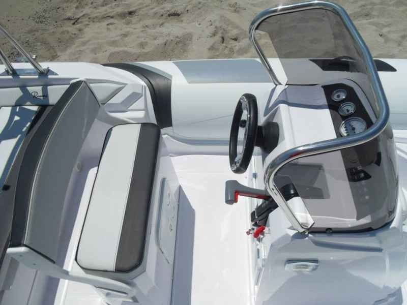 Boat cockpit with black-and-white seats and steering wheel, viewed from above on the water