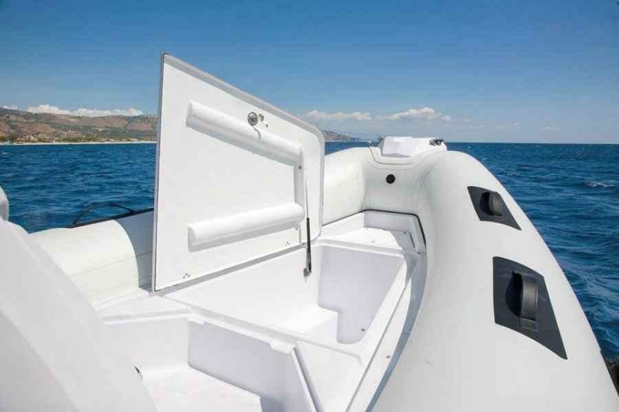 White boat deck with an open hatch on a blue sea under a clear sky