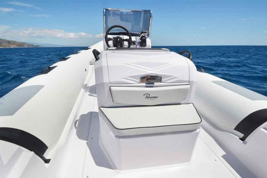 White boat deck with center console and steering wheel on calm blue ocean under clear sky