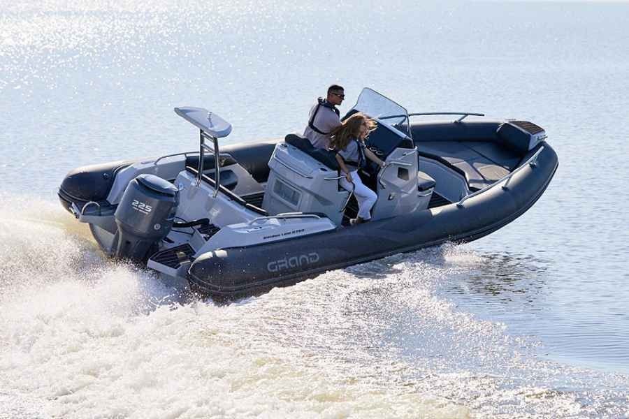 Gray speedboat with two people riding across choppy water, leaving a white wake