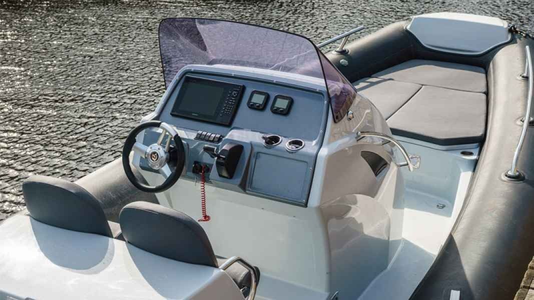 Open grand golden line 850 boat cockpit with steering wheel, dashboard, and gray seats on the water
