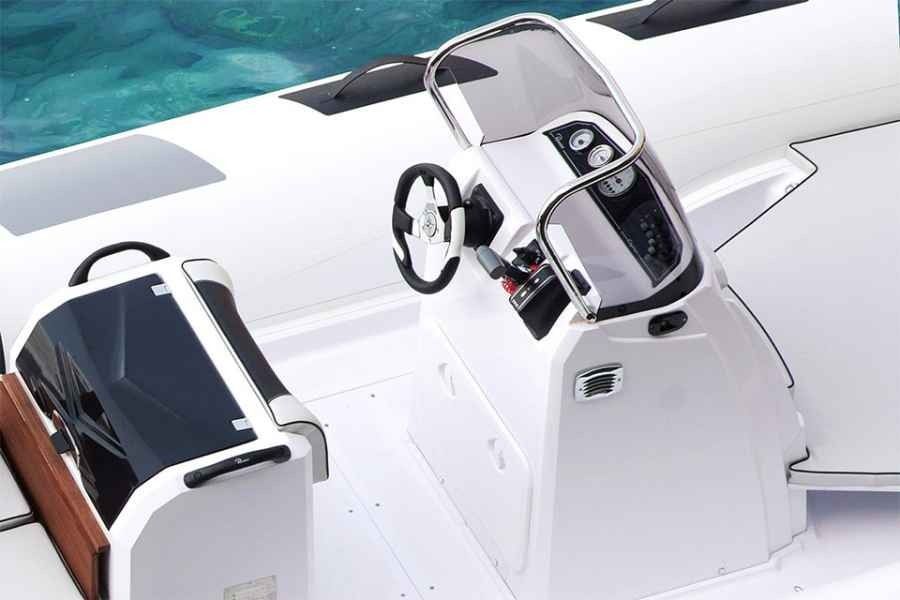 White ranieri cayman 23 sport boat cockpit with steering wheel, seats, and control panel beside blue water