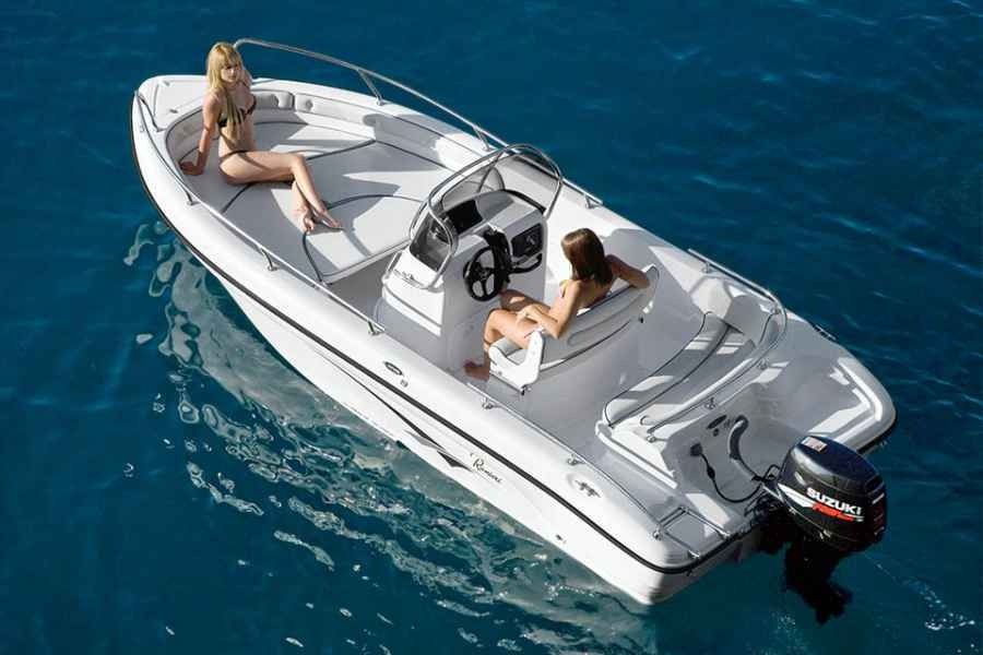 Two people lounging on a white ranieri voyager 19 motorboat in blue open water