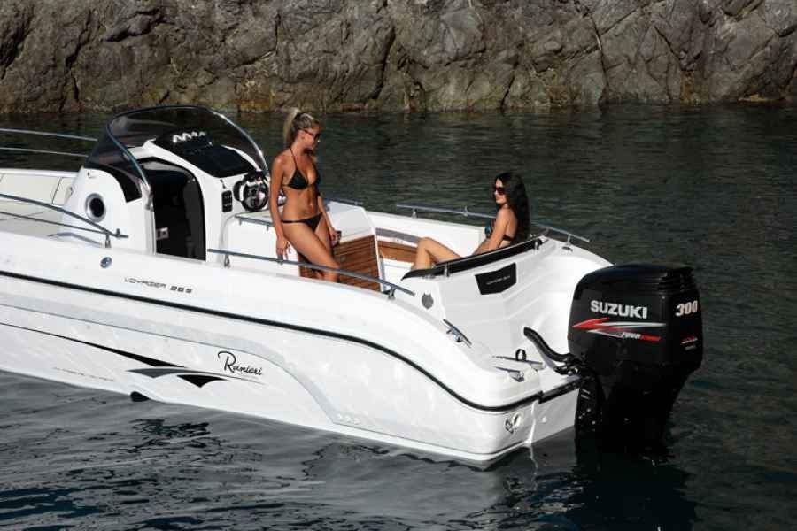 White speedboat with two people on calm water near rocky cliffs