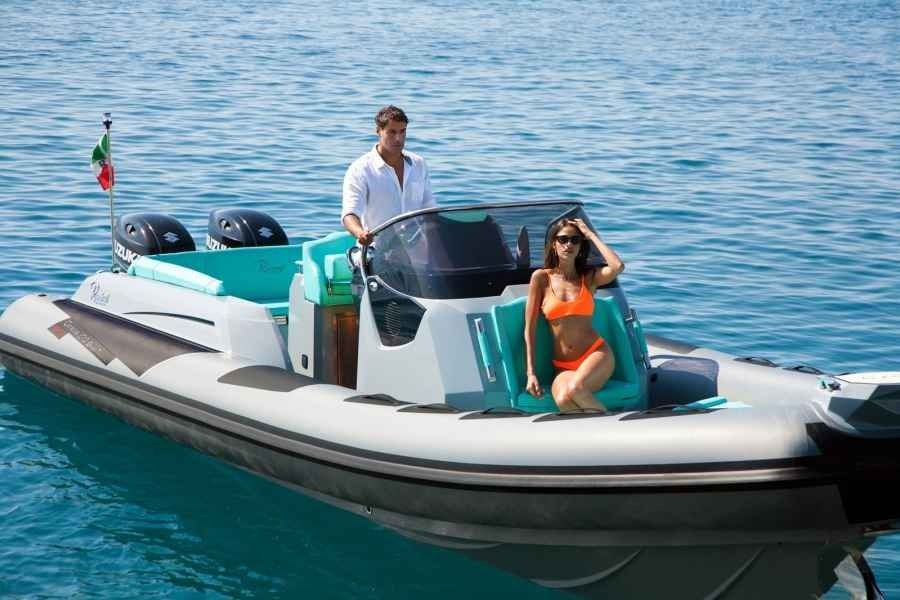 Two people on a teal and white speedboat on calm blue water