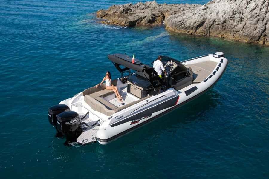 White motorboat cruising in clear blue water near rocky coastline, with two people on deck