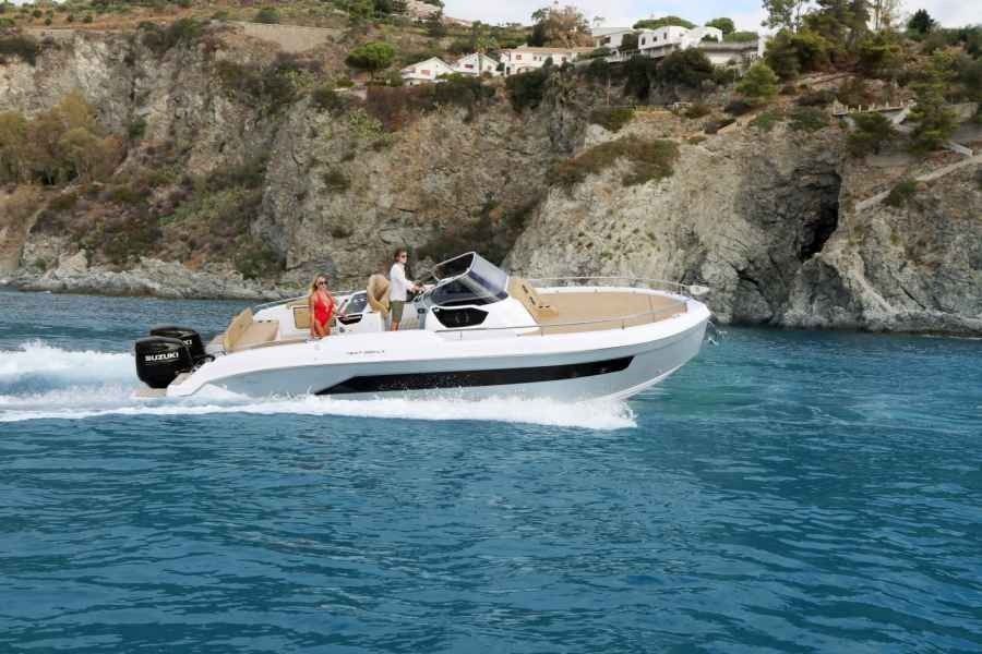 People on a white speedboat cruising on blue water near rocky cliffs