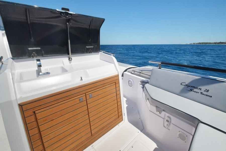 Boat cockpit with white seating, wood cabinet, and blue ocean view