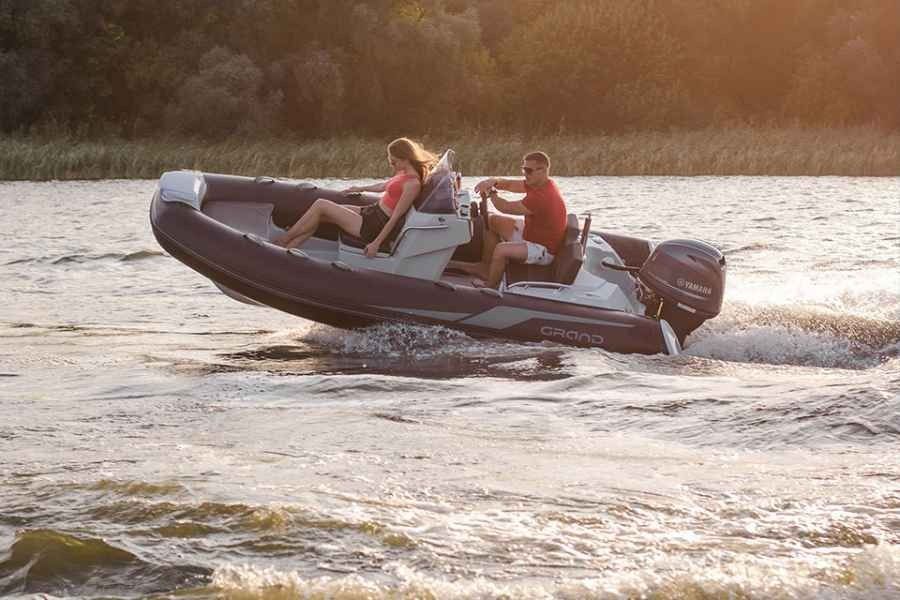 Three people riding a small motorboat across sunlit water at sunset