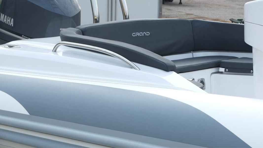 Gray and white grand golden line 850 boat with black cushioned seating at a dock