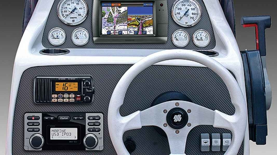 Boat helm with steering wheel, gauges, and navigation screen in a gray dashboard
