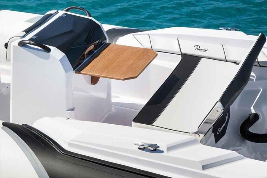 White and black boat seating area with a wooden table and blue cushion on the deck