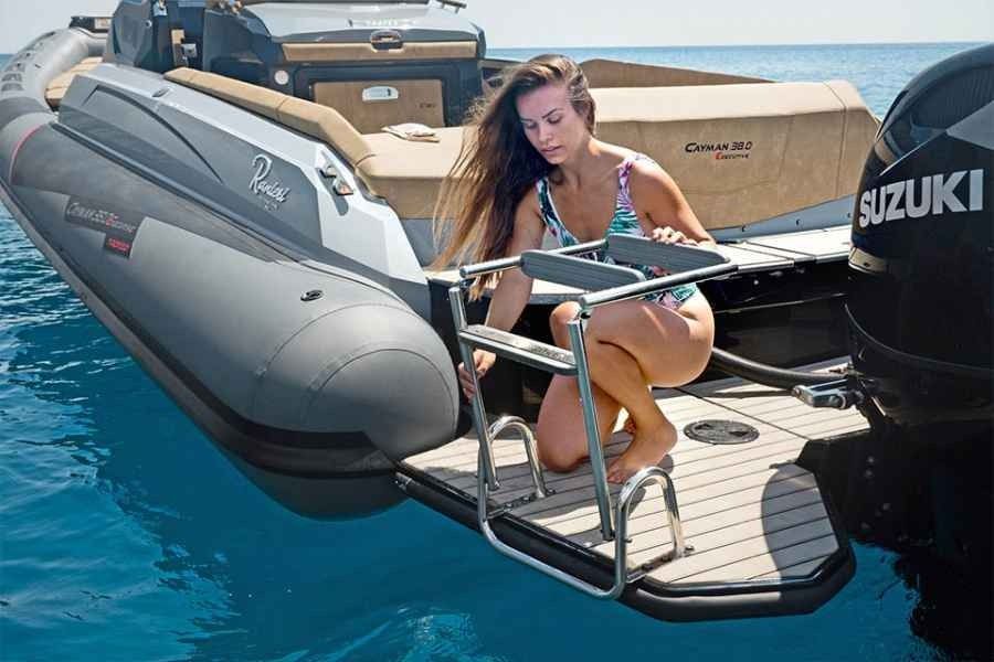 Woman crouching on a boat swim platform beside a Suzuki outboard motor on clear blue water