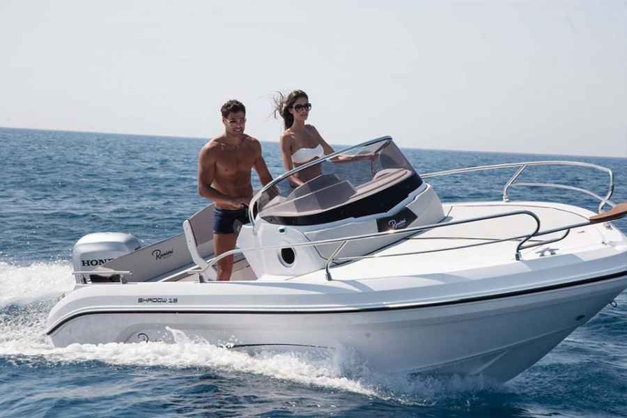 Two people on a white speedboat cruising on open water under a clear sky