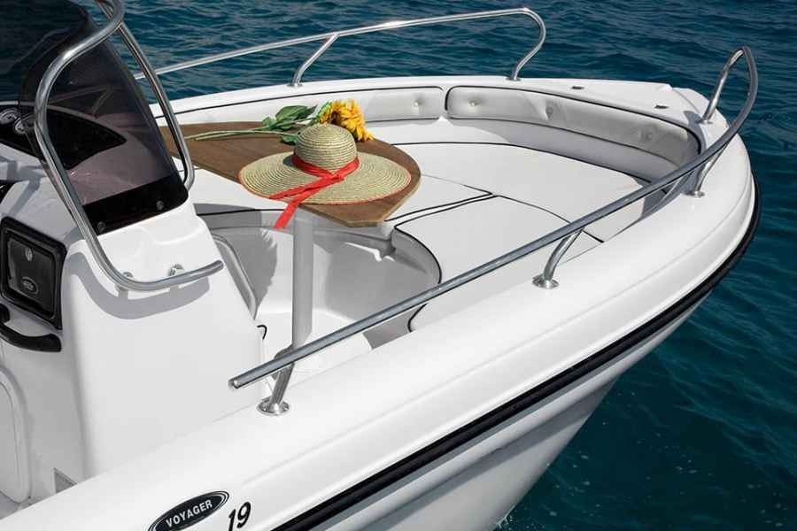White motorboat bow on blue water with a round table holding fruit and a red ribbon