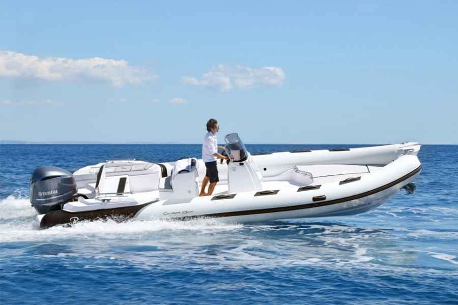 White speedboat on blue water with a person standing on deck under a clear sky