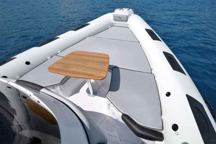 Ranieri Cayman 31 Sport Touring Rib Inflatable boat bow with a wooden table on deck, floating on blue water.