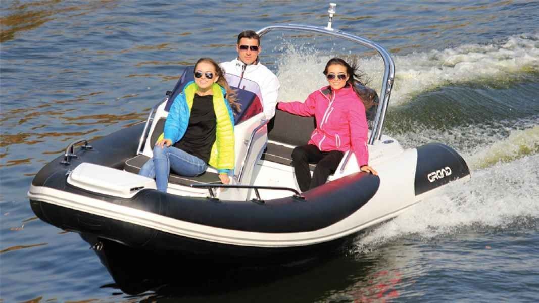 Three people riding in a black-and-white inflatable speedboat on choppy water.