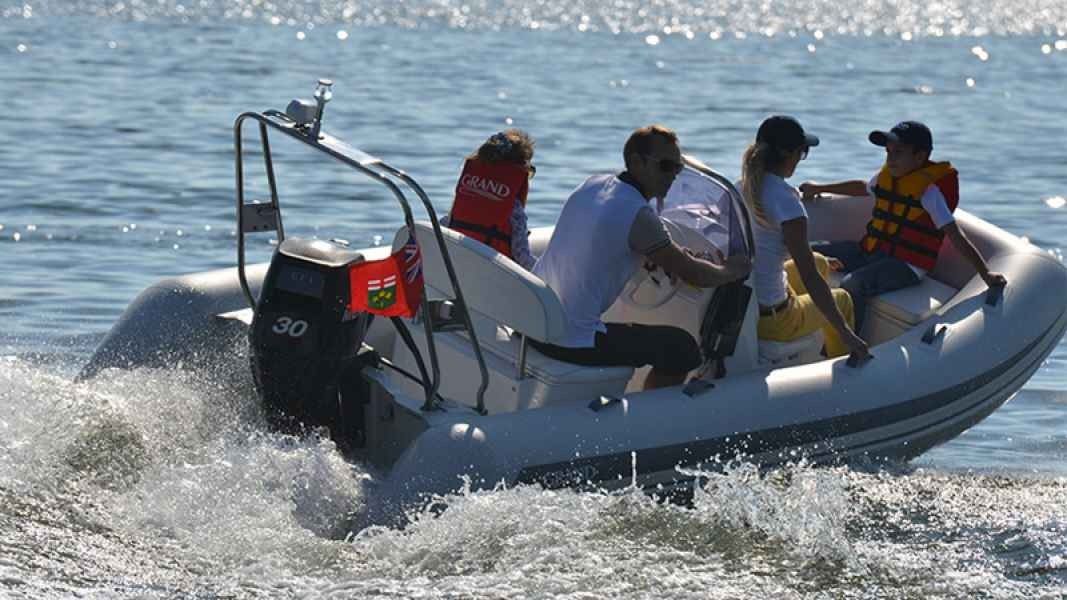 Small inflatable motorboat speeding across choppy water with four people aboard and spray splashing behind