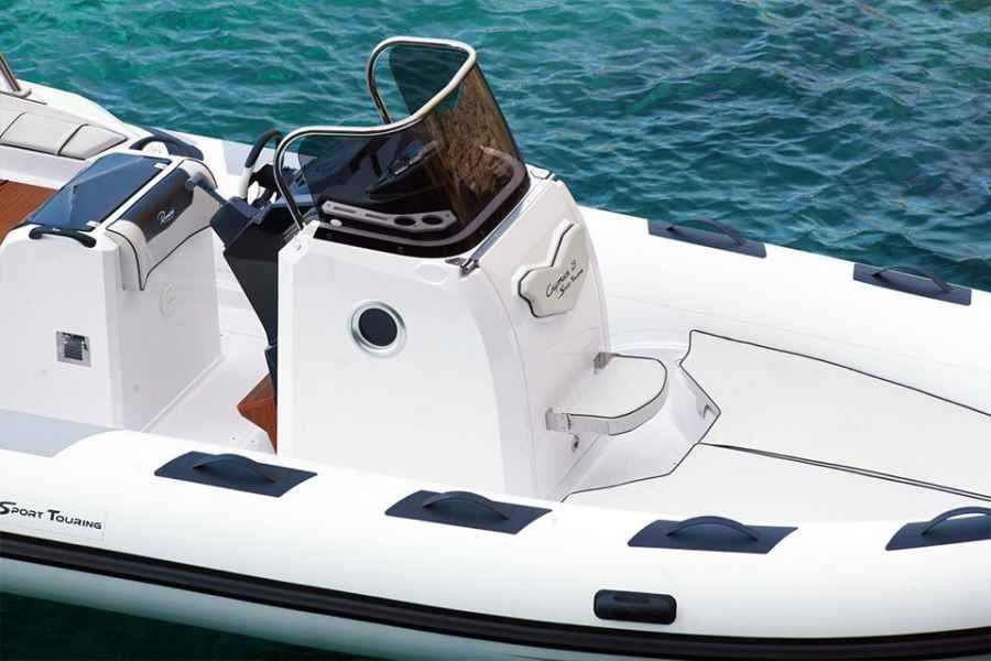 White luxury Ranieri Cayman 23 Sport Touring Rib boat deck with black hatches and a central captain’s chair on blue water