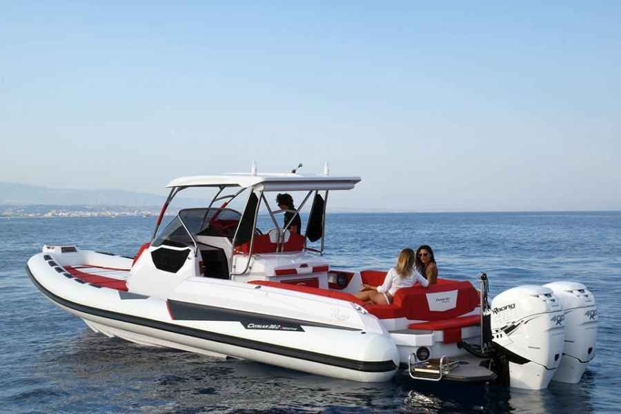 White and red ranieri cayman 38 executive motorboat cruising on calm water with two people seated at the stern