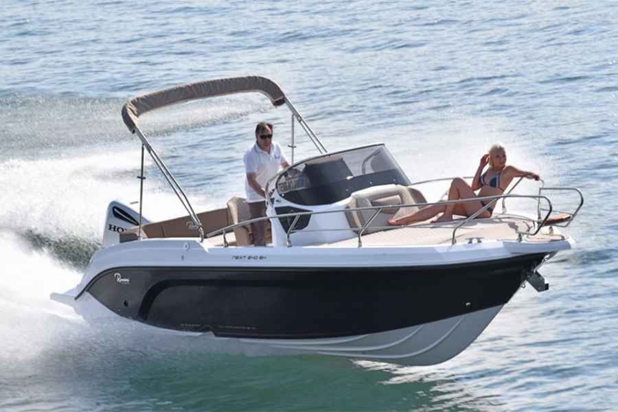 Two people on a Ranieri next 240 motorboat cruising on calm water under a canopy