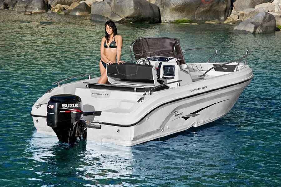 Woman sitting on a white motorboat on clear water near rocky shore