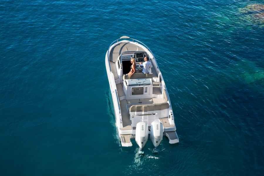 Aerial view of a white motorboat cruising on clear blue ocean water.