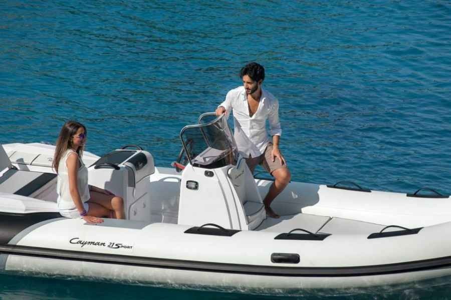 Two people on a white inflatable grand silver line 370 boat on blue water, one seated and one steering