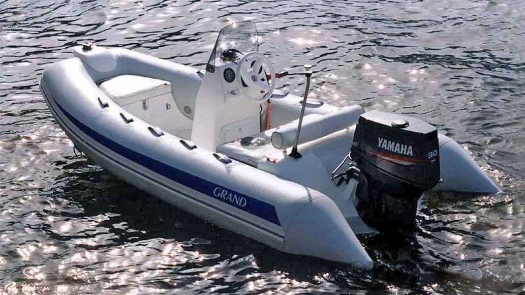 Gray inflatable motorboat on rippling water with a black outboard engine