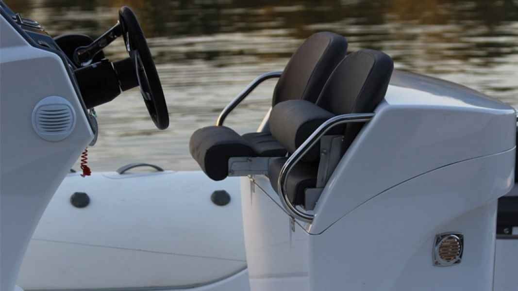 grand golden line 850 Boat helm seat and captain’s chair on a white motorboat near calm water.