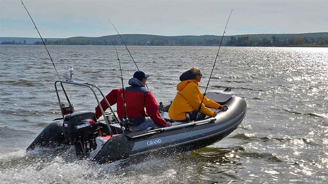 Two anglers in a small boat fishing on sparkling water under a bright sky