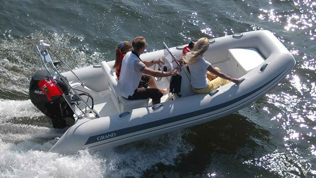 Two people riding in a small gray inflatable motorboat on choppy water