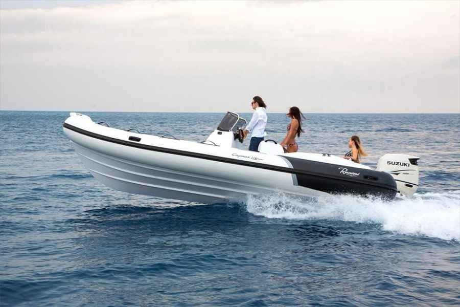 Three people ride a white ranieri cayman 23 sport speedboat skimming across choppy blue water