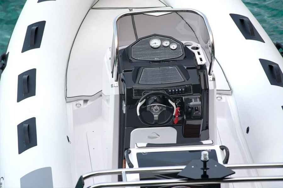 Helm of a white Ranieri Cayman 23 Sport Touring Rib speedboat with black dashboard and steering wheel, viewed from above