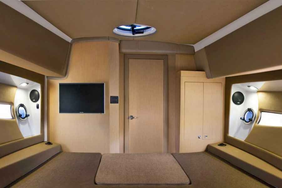 Compact beige cabin interior with twin bunk beds, circular windows, and a closed center door in ranieri 370 executive.
