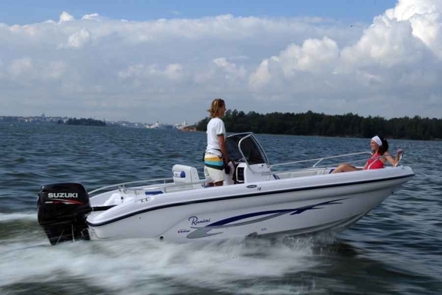 White ranieri voyager 19 speedboat skims across choppy water with two people aboard under a cloudy sky