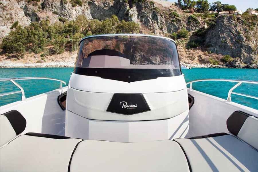 White ranieri voyager 21 Sport speedboat on turquoise water near rocky cliffs, seen from the front deck